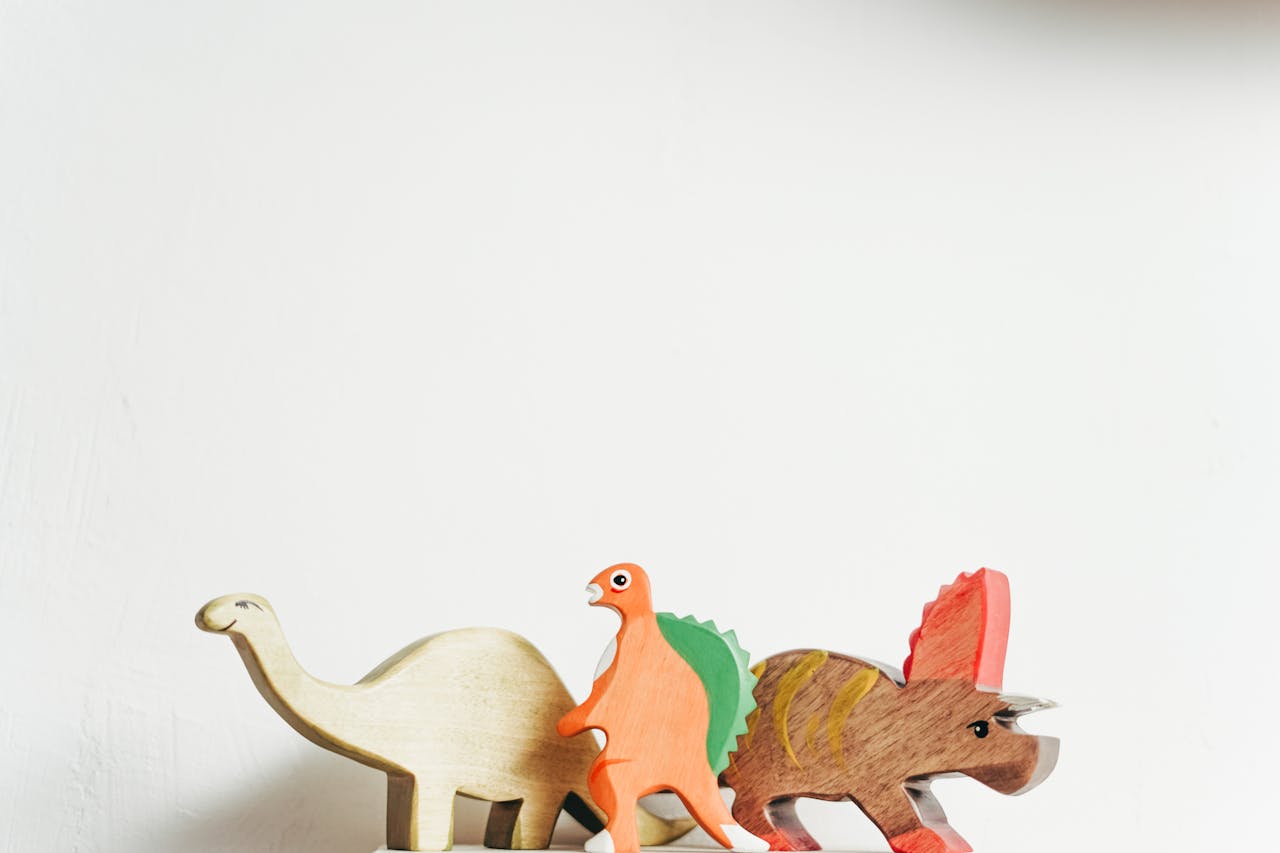 services-03 Three wooden dinosaur toys on a white background showcasing playful creativity.